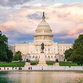 The United States Capitol building at sunset wirh reflection in water.