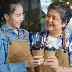 Mother and daughter standing together working at a coffee shop