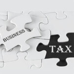 White puzzle pieces with a piece removed with the word "business" written on it reveling the word "tax" under it.