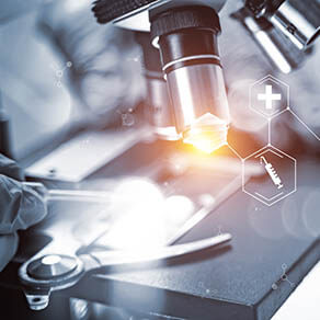 Close up of scientist examining something under a microscope with a light