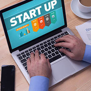 Man working on laptop with START UP on a screen