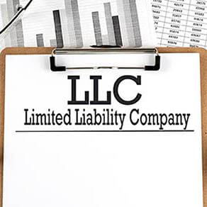 Paper with LLC on chart with calculator,pen and magnifier