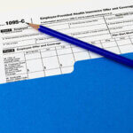 Tax Form 1095-C in a folder with a pencil