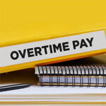 Overtime pay written on the label of a yellow binder