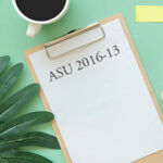 Clipboard with the "ASY 2016-13" written on it with cup of coffee and plant on table