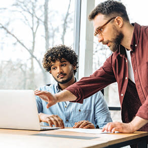 A man showing another man something on a laptop computer