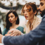 Two women looking at something on a man's phone