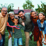 Family of four with their grandparents posing outdoors for a photo