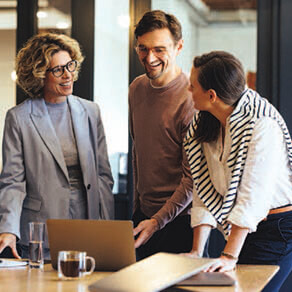 Group of coworkers smiling, in conversation and looking over documents
