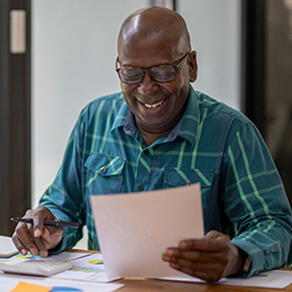 Older man smiling at a table looking at documents