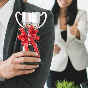 Employee clapping for another employee holding a trophy