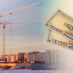 City skyline with construction equipment and close up of hundred dollar bills in front of it