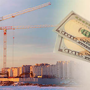 City skyline with construction equipment and close up of hundred dollar bills in front of it
