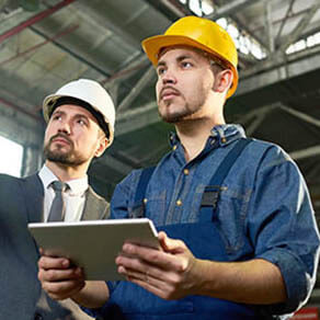 Two men on a manufacturing site looking at an ipad and reviewing a project