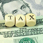 Currency with the word "tax" spelled out in blocks over it