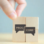 Small blocks with the words "pros" and "cons" and a hand grabbing on the top of the "pros" block