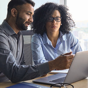 Couple sitting side by side pointing something out on a computer screen