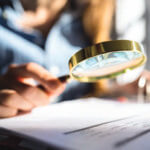 Woman's hand inspecting document with a magnifying glass