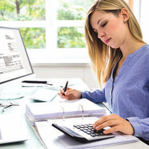Woman working at a computer and using a calculator