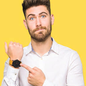 Young man pointing to his watch with disappointment