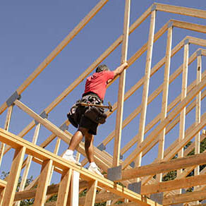 Building contractor carpenter placing new home wood engineered trusses on a residential construction site