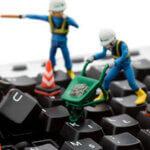 Miniature construction figures repairing a computer keyboard