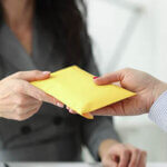 Close up of a woman hands over full envelope to another person