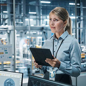 Car Factory Office Concept: Portrait of Successful Female Chief Automotive Engineer Using Tablet Computer to Design and Optimize Automated Robot Arm Assembly Line Manufacturing Electric Vehicles