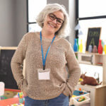 Teacher in a classroom standing with hands on her hips