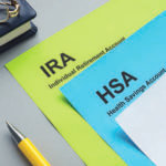 Desk with papers reading "IRA" and "HSA" stacked on top of each other