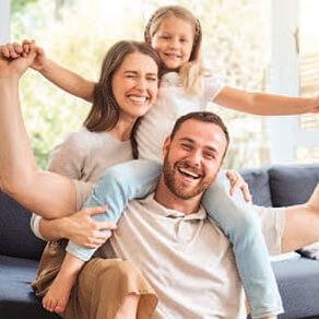 Family photo of husband, wife and daughter smiling and posing for the camera