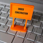 Under construction sign on top of computer keyboard. Computer system under construction, maintenance, repair concept.