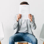 Man covering face with resume in office