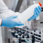 Man worker operator inspecting milk bottles production line dairy factory industry, automatic conveyor for transporting.