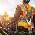 Back of construction man on a site wearing a harness
