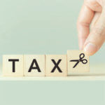 Tiles spelling out the word "TAX" with a hand placing a last title with scissors on it.