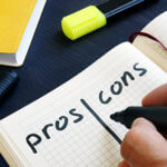 Man is writing list of pros and cons with a black marking pen