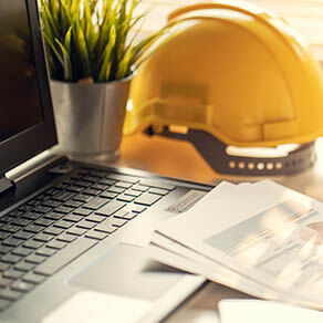 Hard hat, laptop and construction paper work
