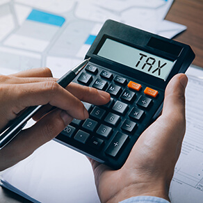Man holding a calculator calculating land sales tax and document