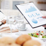 Close-up of open notepad and business document in male hands during business lunch