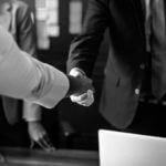 Two men shaking hands one with suit jacket and one without