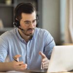 Man with headset; explaining something he is seeing on his computer.