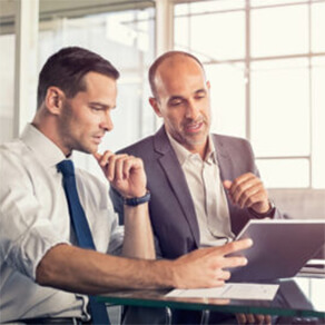 Two businessmen in discussion using computer laptop
