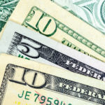 Partial corners of two ten dollar bills, one front view and one back view and a five dollar bill