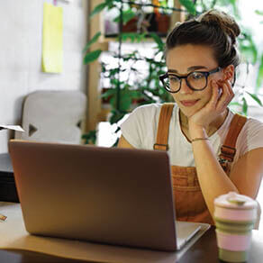 Woman sitting in front of her laptop with her hand resting on her chin