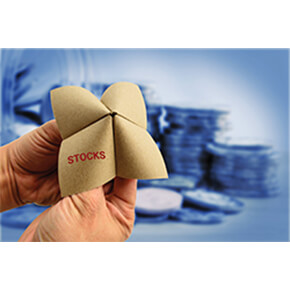 Paper fortune teller showing stocks written on it with coins in the background