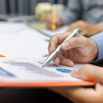 Person pointing at chart on paper with pen