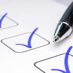 3 checked boxes with blue ink and partial view of pen