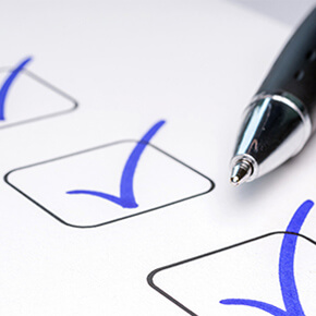 3 checked boxes with blue ink and partial view of pen