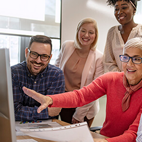 Four adults looking over a computer screen smiling